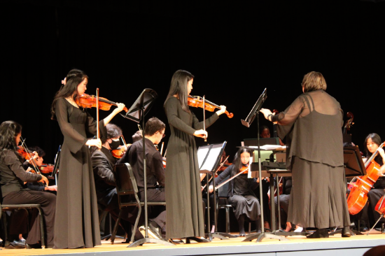 Violinists Isabel Jo ’26 [left] and Kendra Cheng ’25 [right] performing a duet while being accompanied by the orchestra. 